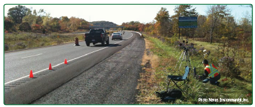 Workers conducting field noise measurement on a rural roadway.