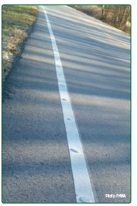 A white edge line with evenly spaced raised pavement markers, also called Botts' dots.
