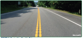 The approach to a curve featuring curve warning signage and edge line rumble strips