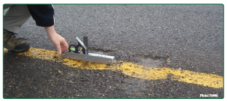 A man measuring the dimensions of a milled rumble strip.