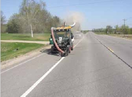 Photo of a vehicle applying fresh paint to pavement markings on a rural road.