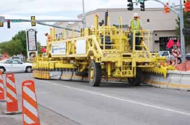 Photo of a zipper truck moving cement barriers.