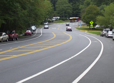 A segment of roadway that includes parallel parking on both sides, dedicated bike lanes, and a center turn lane.