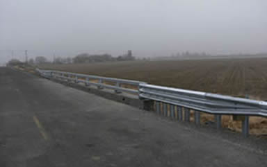 A bridge over a culvert features safety rails.