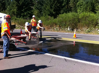 Road workers apply a surface treatment to a roadway.
