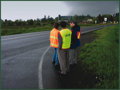 The photo shows a three-person RSA Team at the side of a two-lane rural roadway.