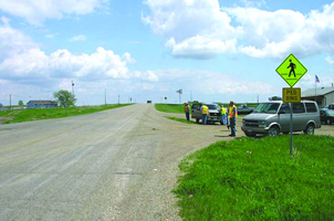 The photo shows BIA 3 / Highway 180 in Kenel, SD: a two-lane rural road with gravel shoulders.  The RSA Team is shown at the side of the road.  A pedestrian crossing sign is provided.