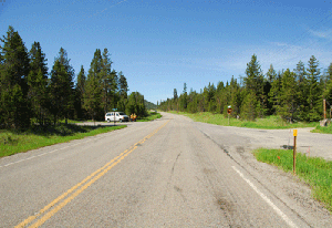 Photo of a westbound view on US Highway 2 approaching Rustic/Gopher Road. The road on the left intersects perpendicular to US Highway 2 while the intersecting road on the right has a skewed approach.