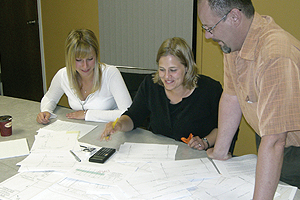  Photo showing three people at a table reviewing drawings. 