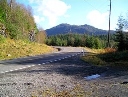 Photo of a paved and marked rural roadway curving around a hill.