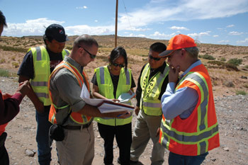 Page 4 photo. This image shows 6 individuals in safety vests discussing something during an RSA.