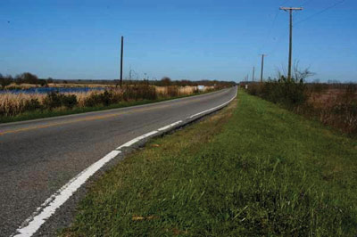 Page 27 photo. This image shows a roadway passing through a wildlife refuge.