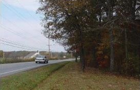 Page v second photo. Image shows a car rounding a curve where trees obstruct the sight distance.