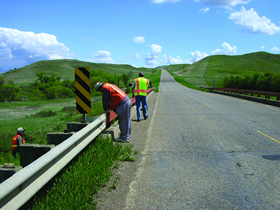 Photo. RSA field review. Members of an audit team inspect guardrail at a project locations.