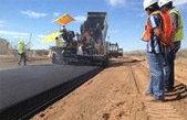 Photograph of a road crew laying down tar on a new roadway