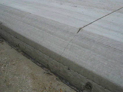photo of freshly cured PCC pavement with SafetyEdge that has been saw cut across the surface and crack has appropriately developed across the angle of the SafetyEdge and down the vertical edge all in alignment.