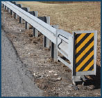 Photo of a barrier along the side of a road with hazard stripes on the end.
