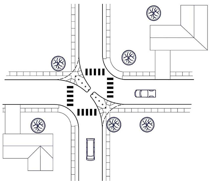 Figure 3.21.1. Diagonal Diverter Schematic. This figure contains a schematic of a four leg intersection which has been turned into two two leg intersections by the placement of a diagonal diverter running from top left corner to bottom right corner of the intersection. The diverter consists of long, narrow curb extensions coming off of opposite facing corners. A channel between the two extensions would allow for bicycle traffic. The streets are lined by sidewalks. Houses occupy the top right and bottom left quadrant of the schematic. Vehicles can be seen in the bottom leg and right leg of the intersections.