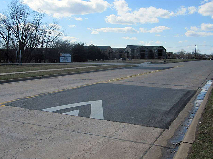 Figure 5.2. Offset Speed Table with Raised Markers Between the Offset. This figure contains a photograph of a wide road near an apartment complex with an offset speed table with raised markers between the offset.