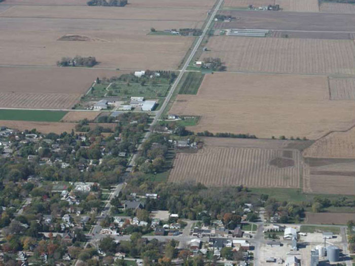 Figure 1-2 - Typical rural community with rural road transitioning into a Main Street environment. (Image Source: Neal Hawkins) Overhead photo of rural community next to fields and farms.