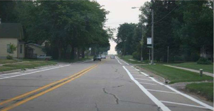 Figure 5-3 Pavement markings used to narrow lanes in Roland, IA (Image Source: Hallmark, et al. 2002). This photo shows the two-lane residential street with white pavement markings on the side to narrow the lanes.