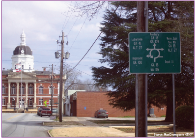 The approach to the roundabout at the Meriweather County Courthouse features a complicated sign with both instructions for navigating the traffic circle as well as directional information for drivers needing to reach specific locations. Source: Max Dromgoole, GDOT