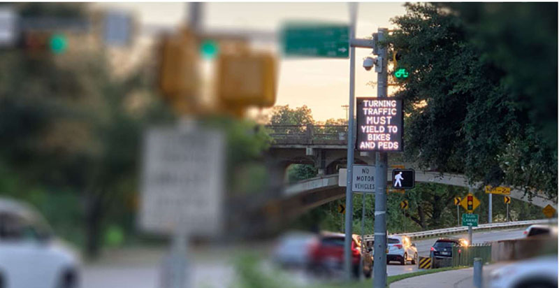 Photo of Austin's busy multimodal roadways depicting an intersection with a crosswalk sign and another sign that reads Turning traffic must yield to bikes and peds.