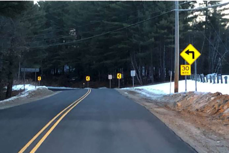 Photo of curve warning signage in Wakefield, NH. The road veers to the left with signage that indicates the curve warning and a 30mph speed limit.