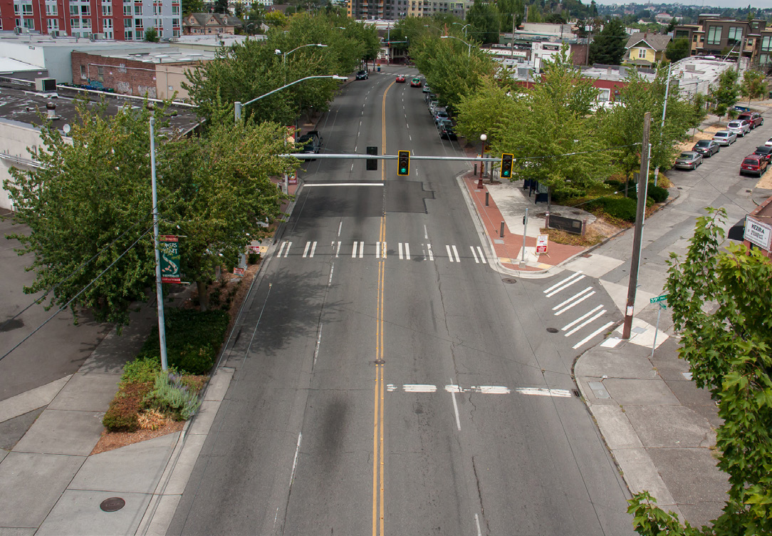 Photo shows a four lane road with two yellow lines in the middle.