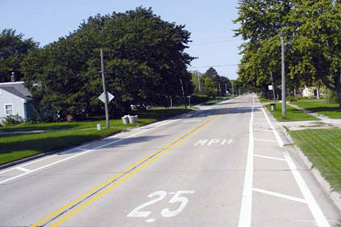Photo shows a lane that reads 25 MPH and has pavement markings between the lane and the curb to show a narrower lane width.
