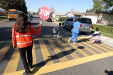 Photograph of a volunteer crossing guard helping children cross the road safely